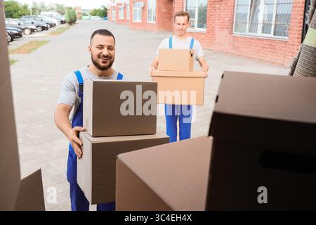 Male movers unloading boxes from car outdoors Stock Photo