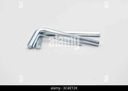 Three metal L-shaped hex keys of varying sizes arranged on a white surface. Stock Photo