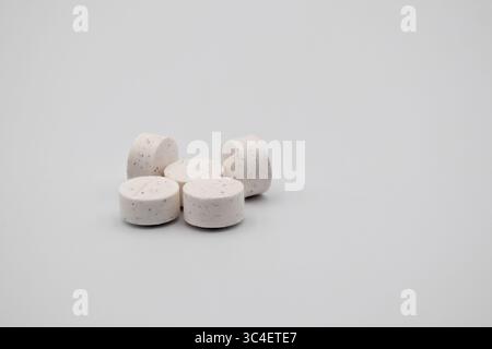 Six round white tablets with speckles, placed neatly on a clean, neutral surface. Stock Photo