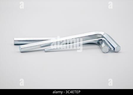 Three metal L-shaped hex keys of varying sizes arranged on a white surface. Stock Photo