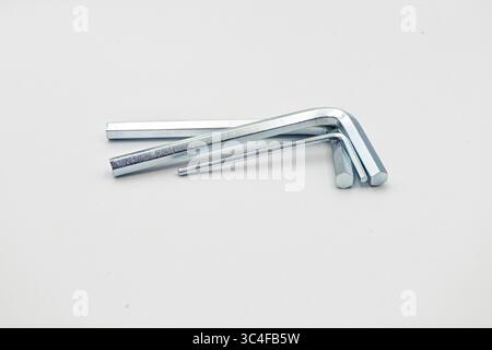 Three metal L-shaped hex keys of varying sizes arranged on a white surface. Stock Photo