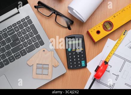Creative layout of architects with roll drawings, architectural project plan, engineering tools and stationery, laptop on table, workspace. Top view. Stock Photo