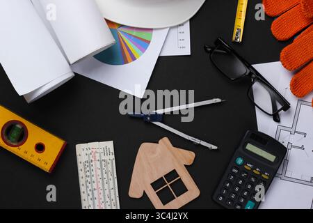 Creative layout of architects with roll drawings, architectural project plan, engineering tools and stationery on black background, workspace. Top vie Stock Photo