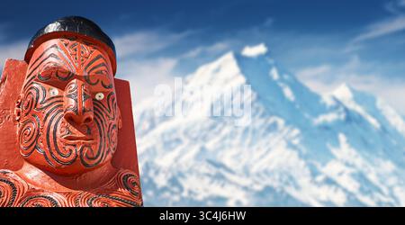 Traditional wooden Maori carved sculpture on a snowy mountains of New Zealand background Stock Photo
