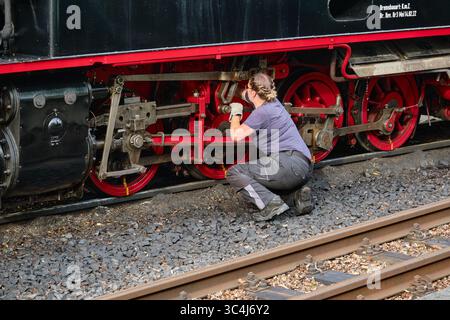 July 6, 2025 - Sellin-Germany: A female engineer performs maintenance on the wheels and rods of a historic steam locomotive on the Rasender Roland her Stock Photo