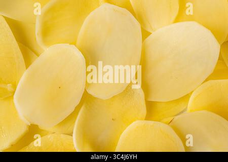 Slices of raw potatoes, thinly sliced to make chips. Background with the texture of raw potatoes. Close-up, top view. High quality photo Stock Photo