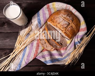 A beautiful arrangement featuring freshly baked bread, sliced and presented on a colorful towel, accompanied by a glass of milk Stock Photo