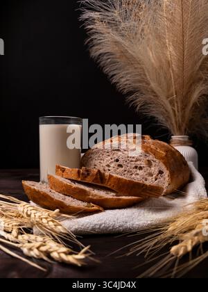 Freshly baked rustic bread accompanied by a glass of milk, with elegant wheat decor creating a warm and inviting atmosphere Stock Photo