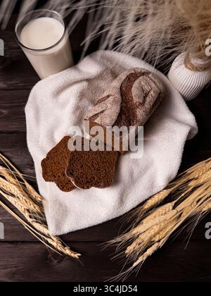 A cozy still life featuring dark rye bread slices, a glass of milk, and decorative wheat, capturing a warm and inviting atmosphere Stock Photo
