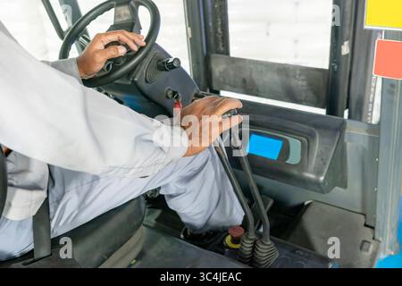 Worker operator controls a forklift inside a warehouse. Storage, inventory, industry, and logistics Stock Photo