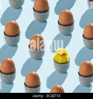 A pattern of brown egg holders with brown eggs. One egg cup has a yellow fluffy chicken in it. Stock Photo