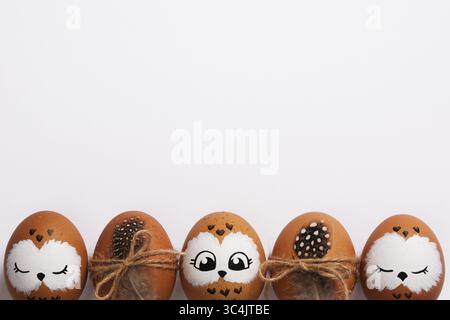 Funny owl family. Brown Easter eggs with painted faces. Space for your text. Stock Photo
