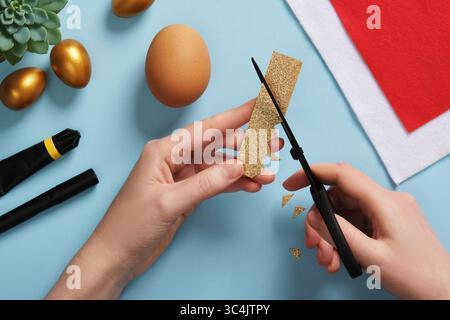 DIY Easter Egg King. Step-by-step instructions. Step 2. Cut a long rectangle out of gold-colored cardboard, then make the teeth of the crown on one si Stock Photo