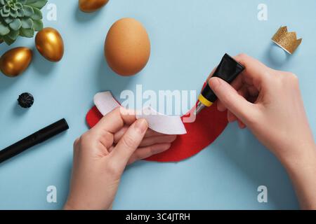 DIY Easter Egg King. Step-by-step instructions. Step 6. Glue the white part of the king's robe to the red part of the robe. Stock Photo