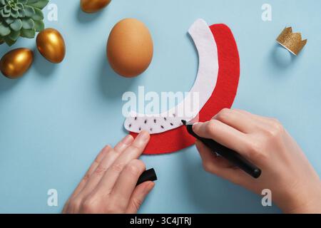 DIY Easter Egg King. Step-by-step instructions. Step 7. Using a black felt-tip pen, make strokes on the white part of the mantle to simulate fur. Stock Photo