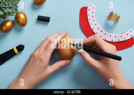 DIY Easter Egg King. Step-by-step instructions. Step 8: On the eggshell, draw the face of the king with a black felt-tip pen. Stock Photo