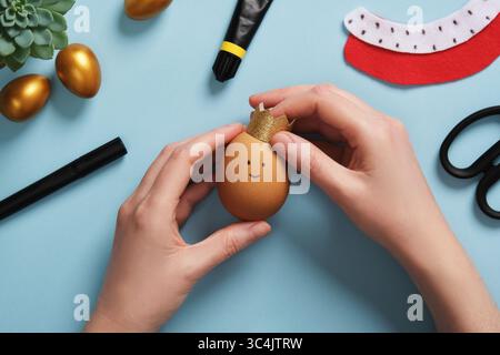DIY Easter Egg King. Step-by-step instructions. Step 9: Attach the crown to the eggshell with glue. Stock Photo