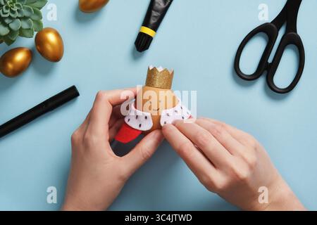 DIY Easter Egg King. Step-by-step instructions. Step 10. Attach the royal robes to the eggshell with glue. Stock Photo