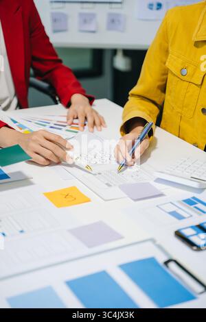 UX developer and ui designer brainstorming about mobile app interface wireframe design with customer breif and color code at modern office. Stock Photo