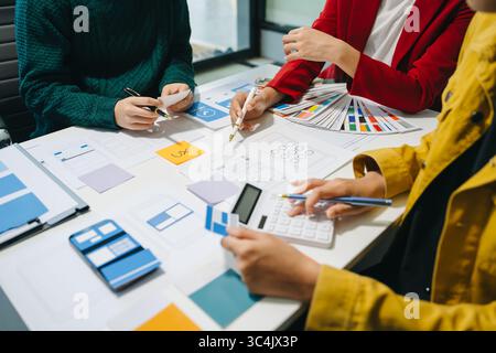 UX developer and ui designer brainstorming about mobile app interface wireframe design with customer breif and color code at modern office. Stock Photo