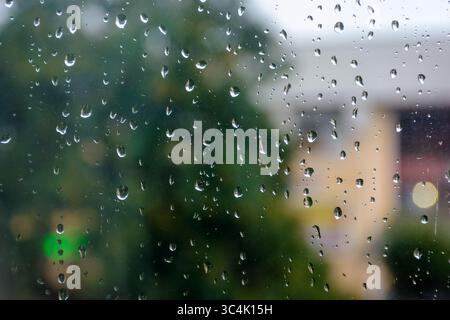 wet window background. rain drop on the glass surface. bad weather concept. urban landscape blurred in the distance Stock Photo