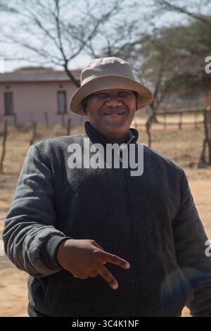 portrait of happy overweight single young man african man , gesture sign victory,l Botswana rural area, outdoors in the yard, house in the background Stock Photo