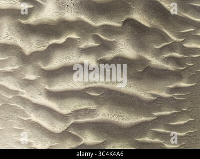 Aerial view of wind-sculpted sand dunes create mesmerizing patterns across the arid landscape, casting long shadows under the harsh desert sun, Namib Desert, Kunene Region, Namibia. Stock Photo
