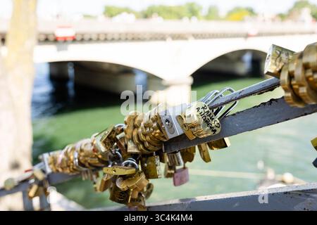 Golden brass love locks padlocks attached to Seine bridge with blurred background Paris Stock Photo