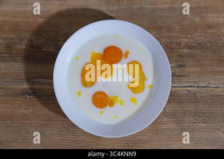 A Delicious Display of Fresh Egg Yolks and Cream Blended Together in a White Bowl Arranged on a Rustic Wooden Table for a Culinary Presentation Stock Photo