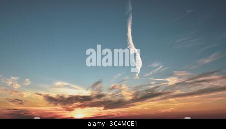 A peaceful sunset sky with cloud layers softly colored by the warm and fading sunlight of twilight. Stock Photo