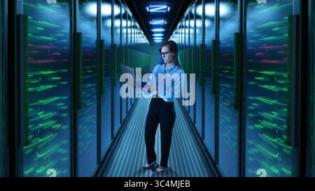 Woman with laptop standing in glowing 3D server corridor Stock Photo