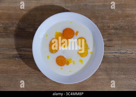 A Delicious Display of Fresh Egg Yolks and Cream Blended Together in a White Bowl Arranged on a Rustic Wooden Table for a Culinary Presentation Stock Photo