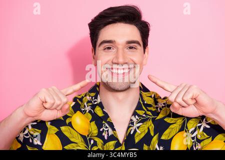 Cheerful young man in tropical print shirt gesturing on pink background with positive energy and a radiant smile Stock Photo