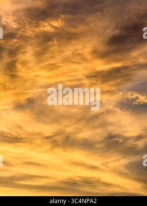 Fiery vertical cloudscape in shades of orange at twilight on a hot evening in mid July, southwest Florida. Light digital oil-painting effect. Stock Photo