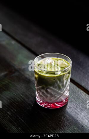 Refreshing iced strawberry matcha latte served on a rustic wooden table in a cozy coffee shop. Aesthetic and colourful layered drink, perfect for a re Stock Photo