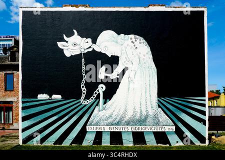 Marijampole, Lithuania- June 21, 2025: A surreal mural by Stasys Eidrigevicius, showing a chained cow and a woman with a hammer Stock Photo