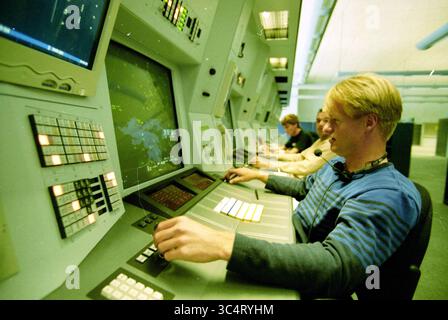 Air traffic control, Schiphol, Schiphol, 04-06-1998 Whizgle News, Dutch Desk, The Netherlands, 1950-2000 A group of individuals is engaged in operating control consoles, focused intently on large screens displaying data. The environment features multiple monitors and an array of buttons and switches, suggesting a high-tech setting where complex tasks are being managed. Stock Photo
