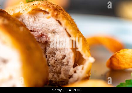 Chicken stuffed with bacon and cheese, fried in lision. A traditional French dish cordon bleu on a blue plate. Close-up. High quality photo Stock Photo