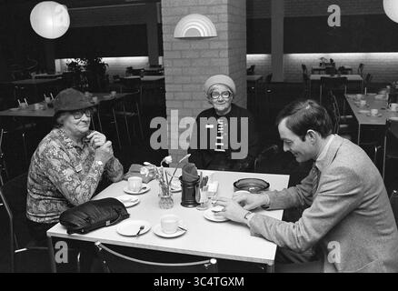 Spectrum retired day de Meern, Spectrum, 11-04-1980 Whizgle News, Dutch Desk, The Netherlands, 1950-2000 Three individuals are seated around a table in a casual setting, enjoying coffee and conversation. Two women, dressed in patterns and hats, are engaged in discussion, while a man, dressed in a suit, interacts with them, creating a warm atmosphere. The table is adorned with small cups, and a minimalistic décor surrounds them. Stock Photo