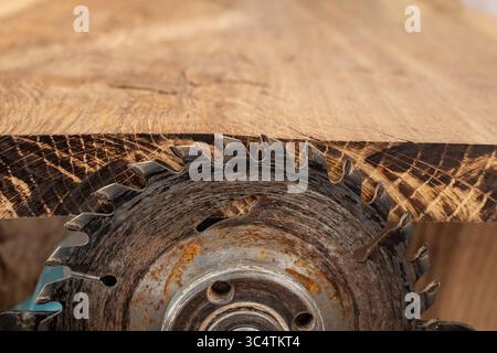 High speed hand grinder with a circular blade cutting hardwood and wood marking the edge Stock Photo