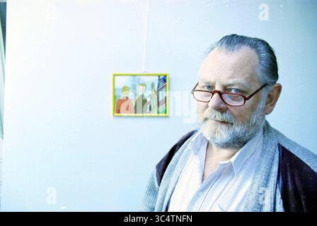 Mr. van Egmond, IJmuiden, IJmuiden, The Netherlands, 02-05-1995 Whizgle News, Dutch Desk, The Netherlands, 1950-2000 A bearded older man wearing glasses stands in front of a colorful artwork. He has a thoughtful expression and is dressed casually in a cardigan over a collared shirt, adding a touch of warmth to the scene. The artwork behind him features two figures in a vibrant setting, contrasting with his contemplative demeanor. Stock Photo