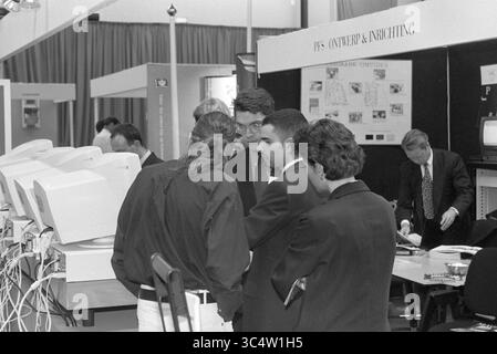 Business Contact Day Hoofddorp, Hoofddorp, The Netherlands, 24-09-1997 Whizgle News, Dutch Desk, The Netherlands, 1950-2000 A group of professionals engaged in a discussion at a technology exhibition, examining computer monitors and networking equipment, while others browse informational displays in the background. Stock Photo