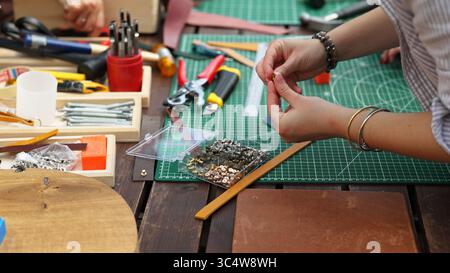 Hands working with leather and metal crafting tools. Stock Photo