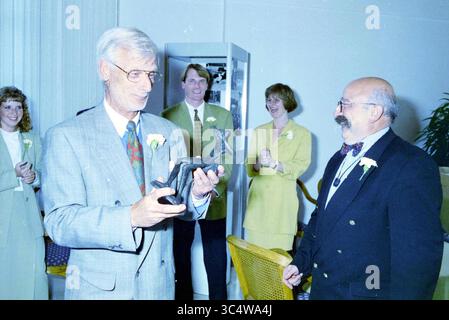 50 years of United Photos de Boer with unveiling of Poppe de Boer statue. Created by Kees Verkade., Haarlem, Parklaan, The Netherlands, 19-05-1995 Whizgle News, Dutch Desk, The Netherlands, 1950-2000 A man in a suit holds a small statue, smiling as he interacts with another man in a bow tie and glasses. Behind them, a group of people is applauding, dressed in formal attire, adding to the celebratory atmosphere of the moment. Stock Photo
