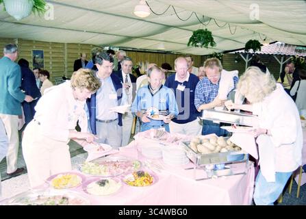 People at a festive gathering, with a running buffet, 00-00-1996 Whizgle News, Dutch Desk, The Netherlands, 1950-2000 A lively gathering features guests enjoying a buffet spread, with various dishes laid out on a table. People are interacting and serving themselves, creating a warm atmosphere of conversation and camaraderie. Stock Photo