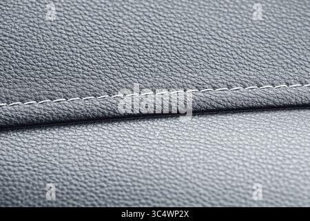 Grey leather texture with seam. Closeup of stitched fabric. Upholstery detail background. Material surface macro. Automotive or furniture element. Stock Photo
