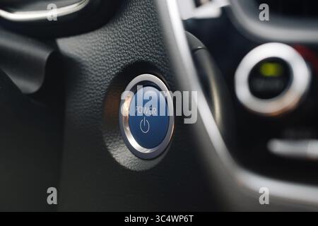 Car power start button. Closeup of vehicle ignition. Modern dashboard detail. Blue engine switch. Automobile interior tech. Engine control concept. Stock Photo