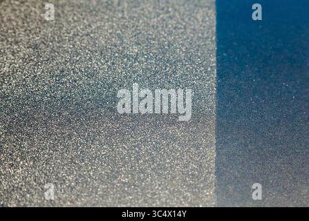 A silvery and dark blue rough surface separated by a straight line. Stock Photo