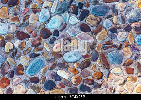 Stones of various shapes and colors are laid out on the road as a sidewalk close-up. Stock Photo