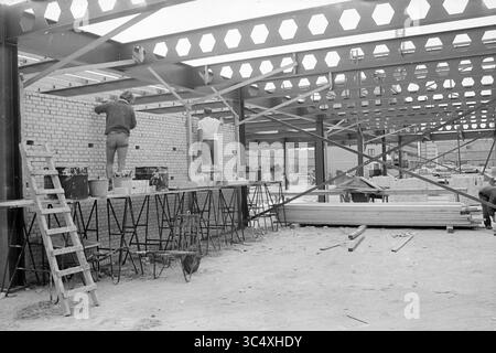 Work in the Meerwijk shopping center, Work, 28-05-1970 Whizgle News, Dutch Desk, The Netherlands, 1950-2000 Workers are engaged in construction, laying bricks and installing framework within a partially built structure. Scaffolding and construction equipment are visible, indicating an active building site. Stock Photo